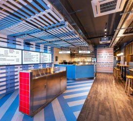 Contemporary restaurant diner featuring illuminated menu boards, pendant lighting, and exposed industrial-style electrical installations, providing a modern and vibrant dining environment.